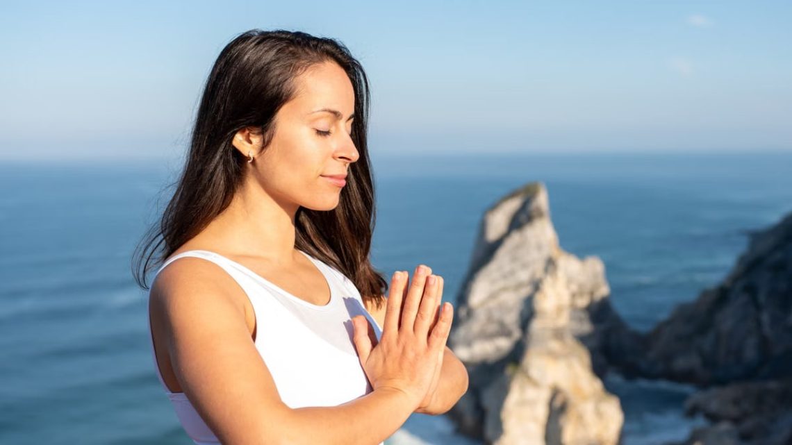 A woman meditates peacefully by the ocean in Portugal, embracing wellness.